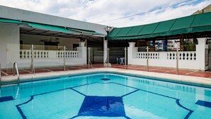 A swimming pool with a geometric tile pattern, surrounded by a white wall with decorative railings and a green awning. - Ayenda 1408 Jaba Santiago de Cali (Cali)