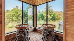 Una habitación con ventanas amplias, suelo de madera y dos radiadores de piedra.