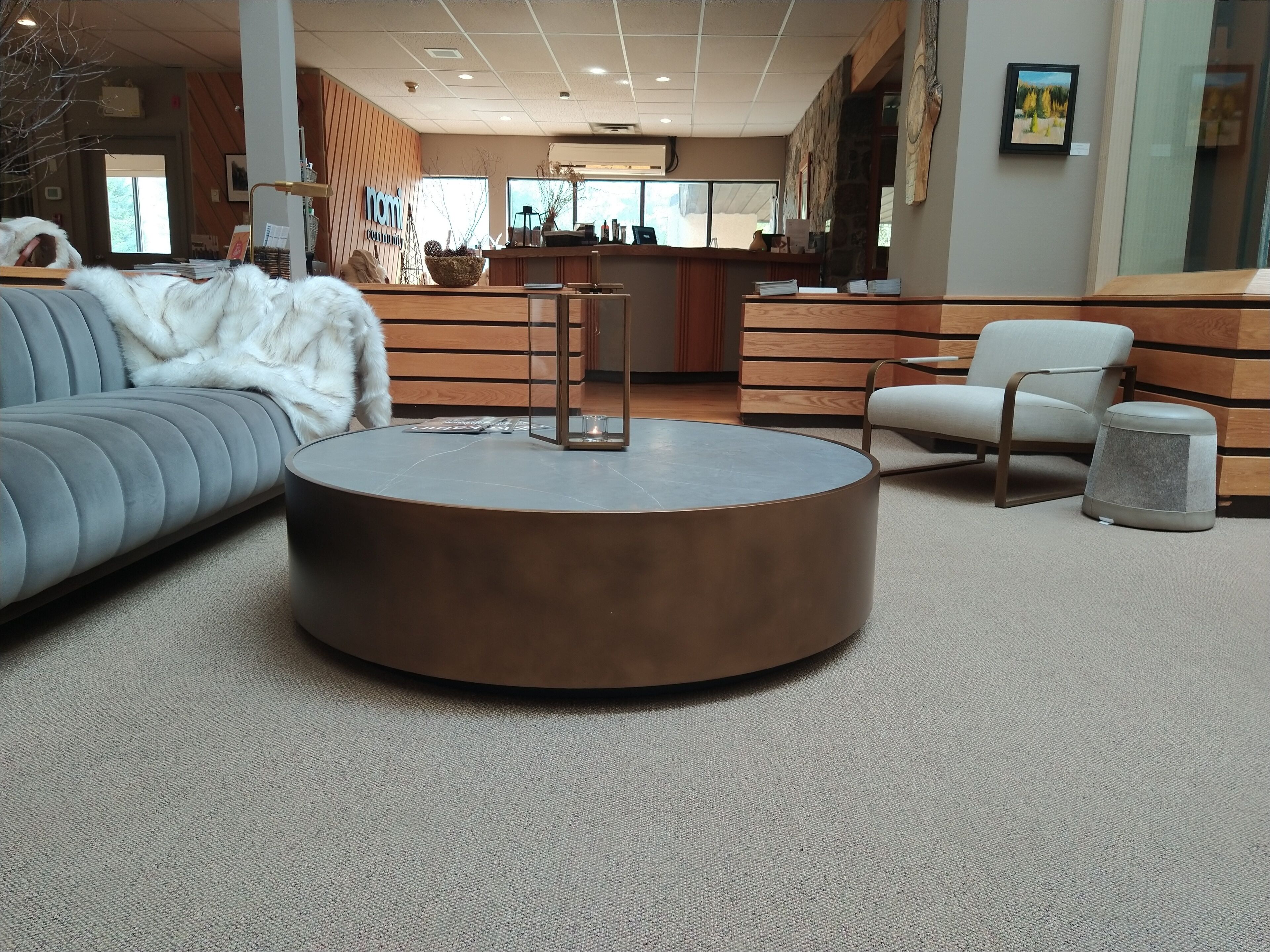 Ein modernes Interieur mit einem runden Couchtisch, einem grauen Sofa und einer weißen Felldecke.