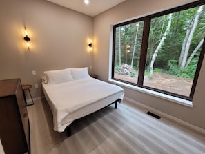 A bedroom with a large window, a bed, and two wall-mounted lights.