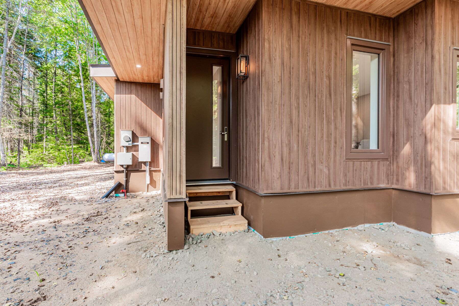 A wooden cabin with a front door, a small porch, and a window.