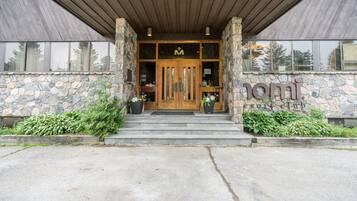 Fachada de piedra con puerta de madera y escalones que conducen a la entrada de un edificio moderno.