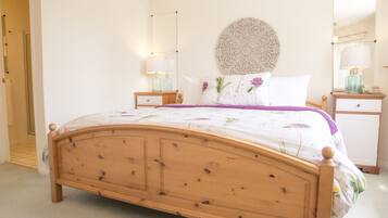 A bedroom with a wooden bed, a round decorative wall piece, two bedside tables with lamps, and a nightstand.