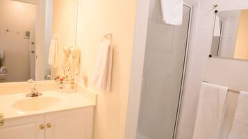 A bathroom with a sink, mirror, and shower.
