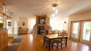 Un'ampia sala da pranzo con camino in pietra, tavolo da pranzo in legno e sedie.