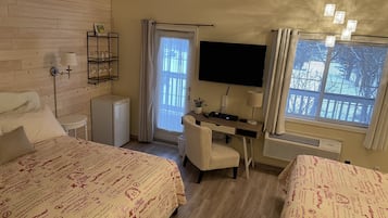 A hotel room with two beds, a desk, a TV, and a window with curtains.