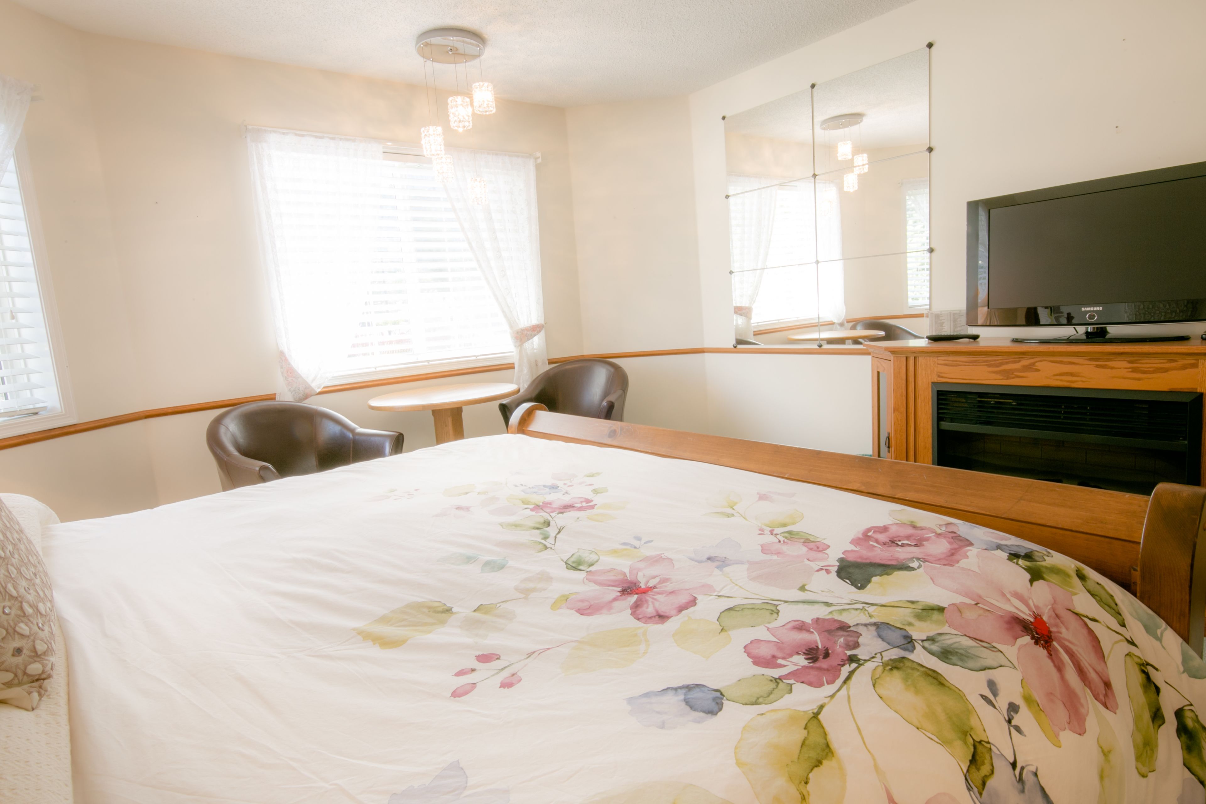A hotel room with a bed, a desk, a chair, a television, and a window with curtains.