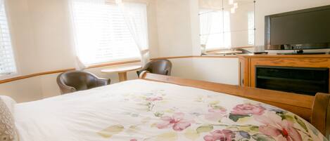 A hotel room with a bed, a desk, a chair, a television, and a window with curtains.