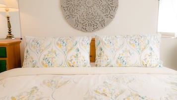 Un lit bien fait, avec une literie à motifs, une décoration murale et une lampe de chevet.