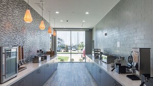 Una cocina moderna con armarios grises, salpicadero de ladrillo e iluminación colgante.