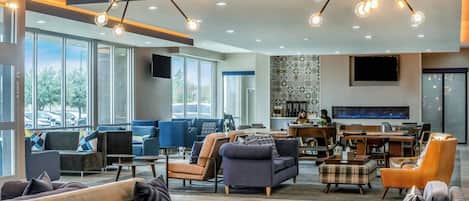 A spacious lobby with seating areas, a fireplace, and large windows offering views of the outdoors.