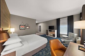 Una habitación de hotel con una cama, un escritorio, una silla, un televisor y una ventana con cortinas.
