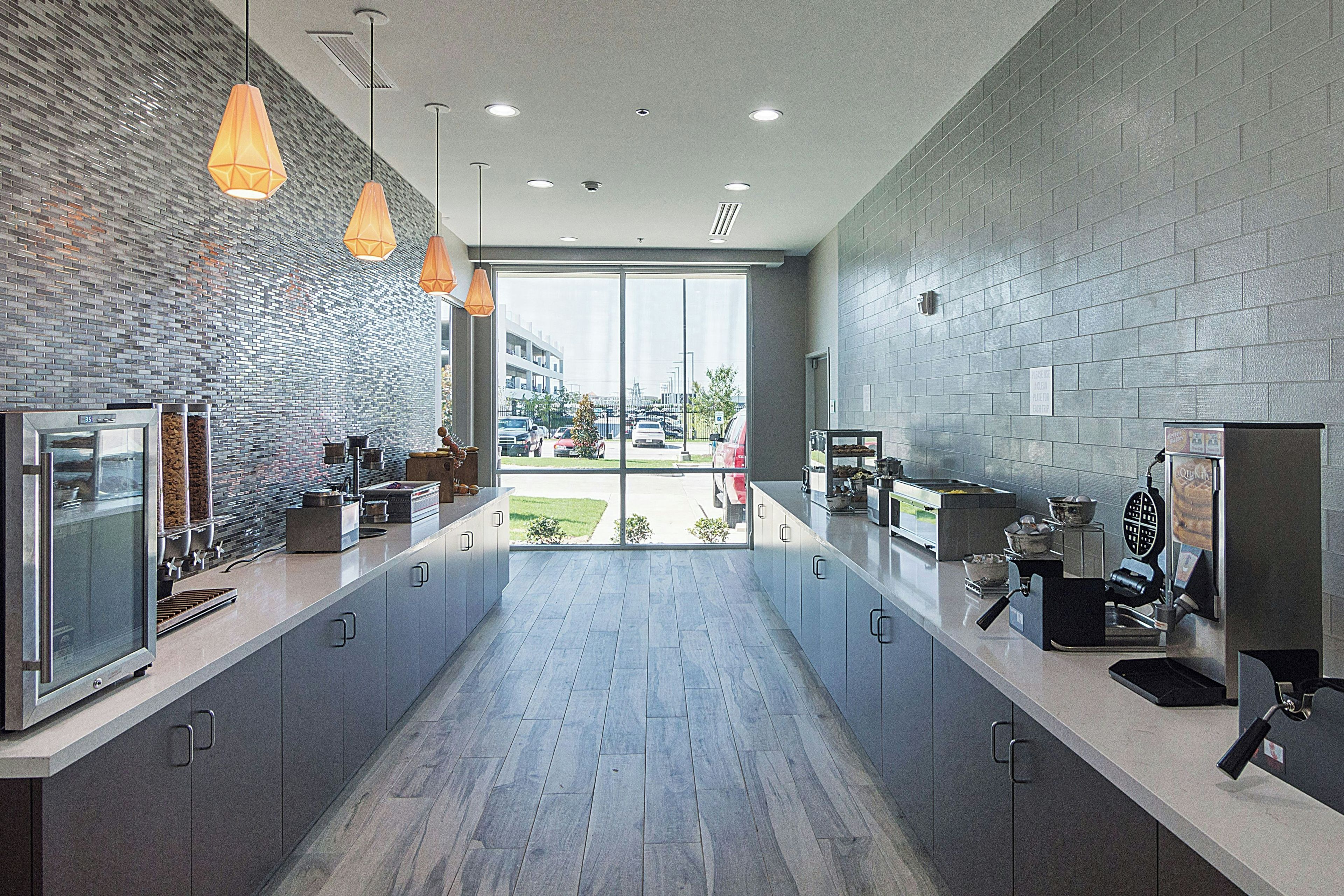 A modern kitchen with a brick backsplash, pendant lighting, and a view to the outside.
