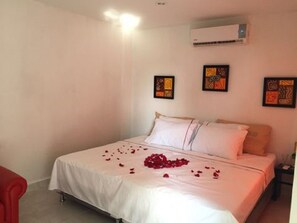 A hotel room with a bed, a nightstand, and a red chair. - Manzanillo Beach (Cartagena)