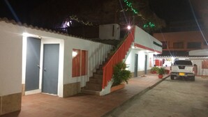 A building with a staircase leading to a door, a parked vehicle, and a small garden area. - Manzanillo Beach (Cartagena)
