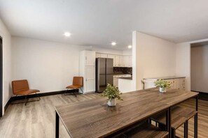 Eine moderne Küche mit weißen Schränken, einem Edelstahlkühlschrank und einem Holzespeisebereich mit Bänken.