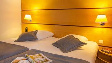 Una habitación de hotel con una cama grande, dos lámparas de noche y una mesita de noche con un libro.