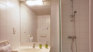 A bathroom with a sink, mirror, and shower. - Le Magendie (Paris)