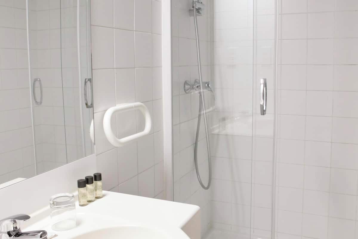 A modern bathroom with a white sink, mirror, and glass-enclosed shower.