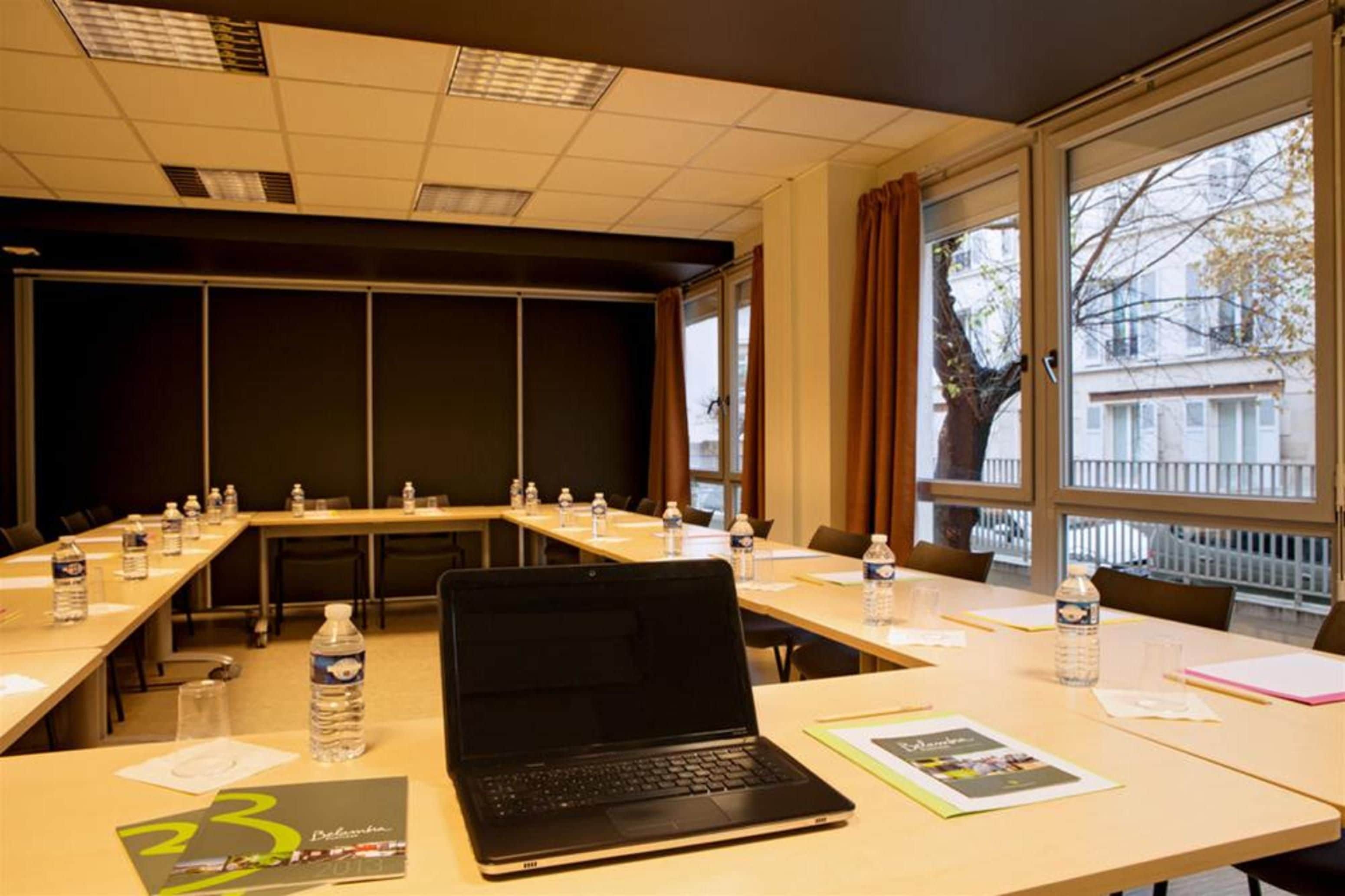 Ein Konferenzraum mit einem langen Tisch, Laptops, Wasserflaschen und Papierlagen.