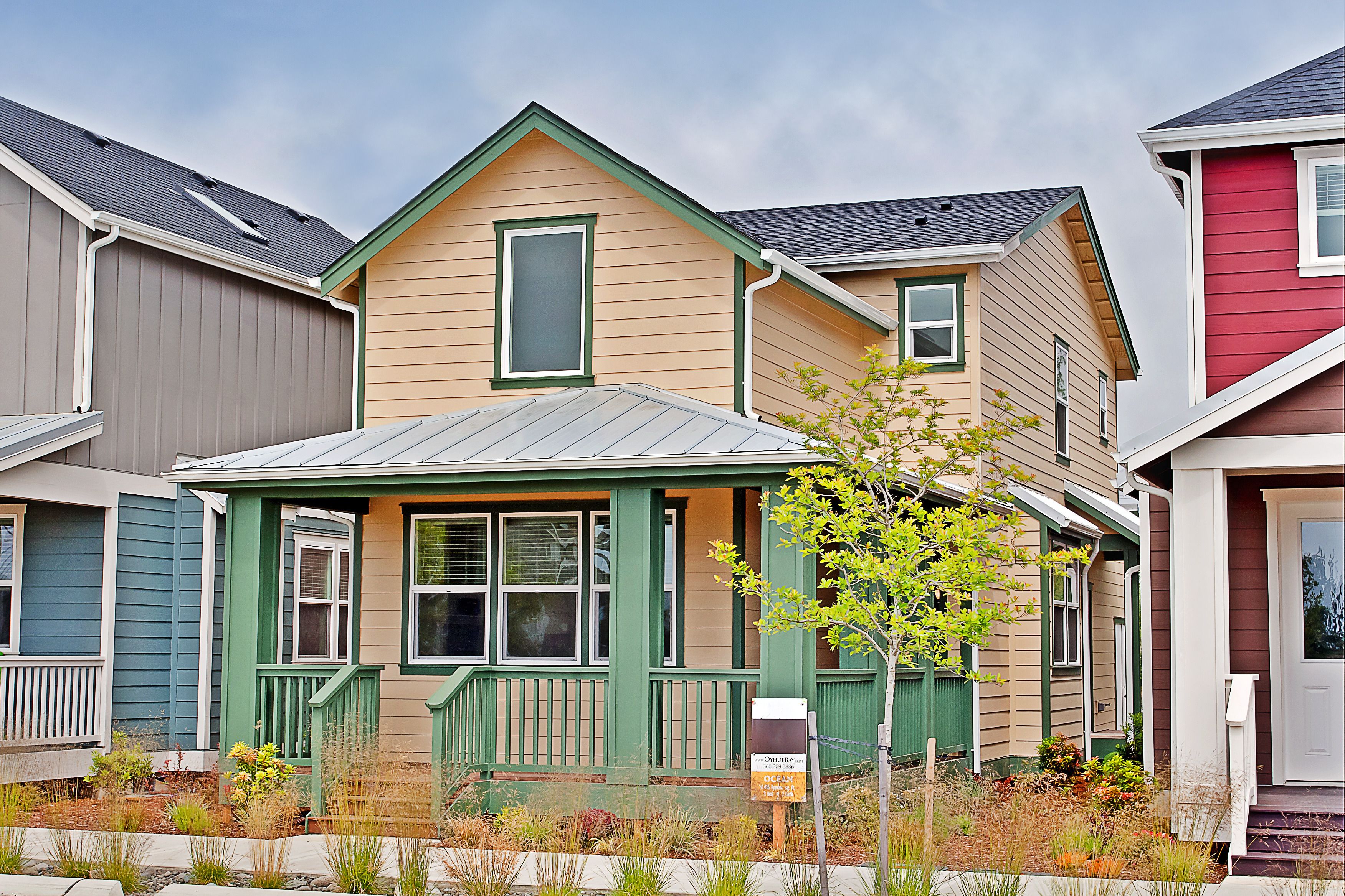 A two-story house with a green front porch and a small garden area in front.