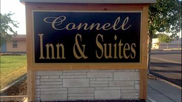 A sign for Connell Inn & Suites with a stone facade and a clear sky in the background.