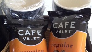 A basket containing two packages of Cafe Valet coffee, one labeled 'regular' and the other 'dark roast'.