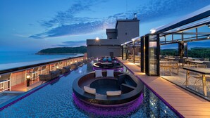 A poolside area with a circular seating arrangement, a view of the sea, and a building with large windows. - Hotel Two - Y (Yangyang)