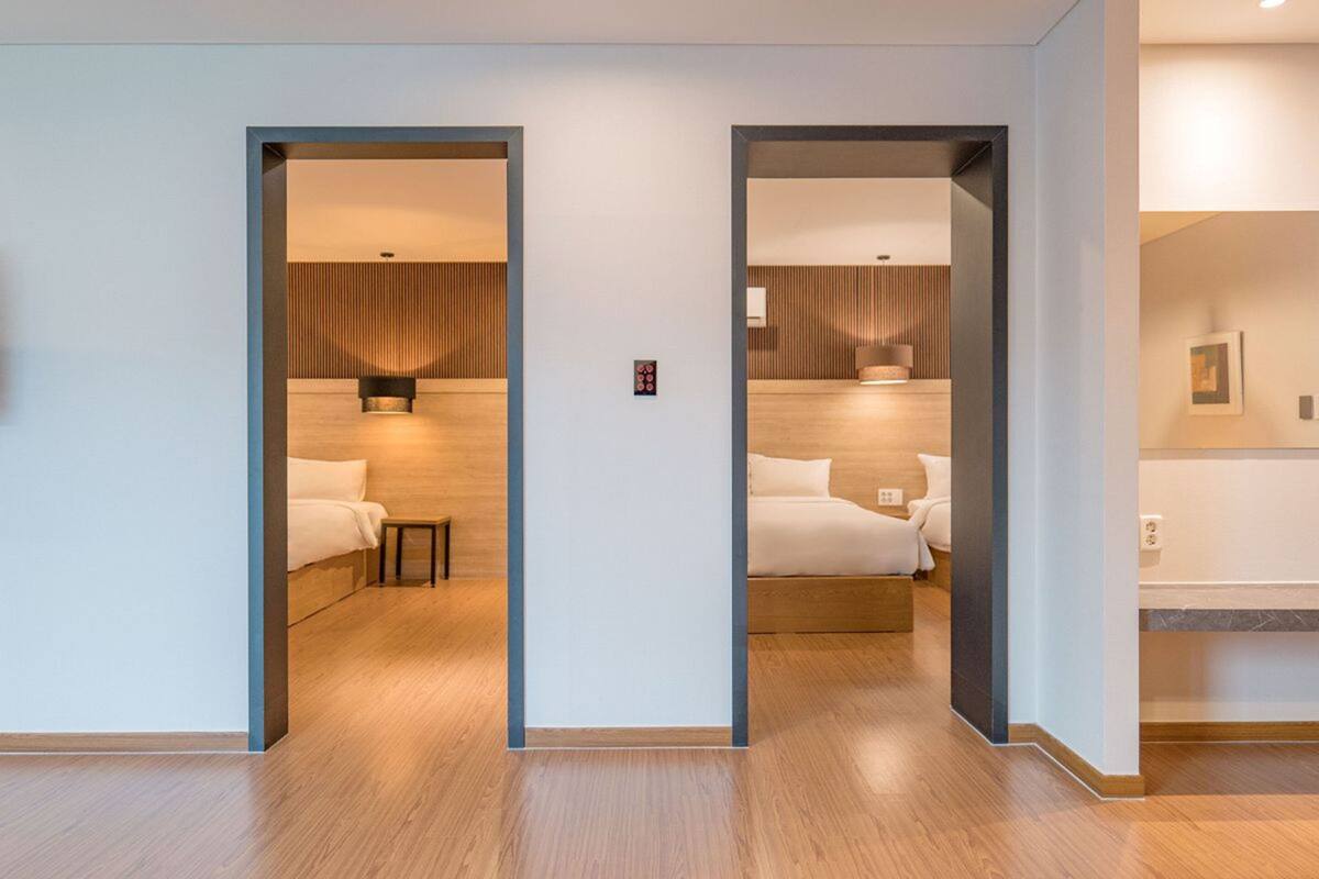 A hotel room with a wooden floor, a bed, a bedside table, and a nightstand.