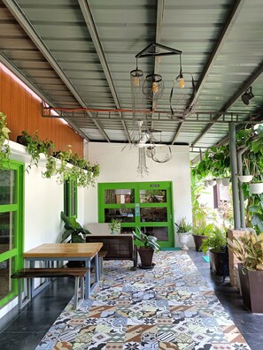 Un área de recepción con una puerta verde, piso estampado y plantas colgantes.