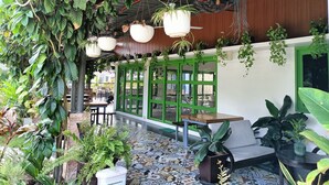 An indoor patio area with hanging plants, a patterned floor, and a seating area with tables and chairs.