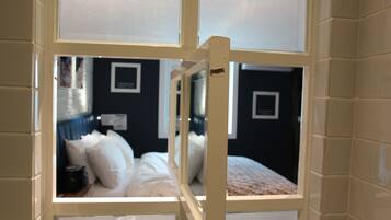 Habitació d'hotel amb un llit, una tauleta de nit i un rellotge penjat a la paret.
