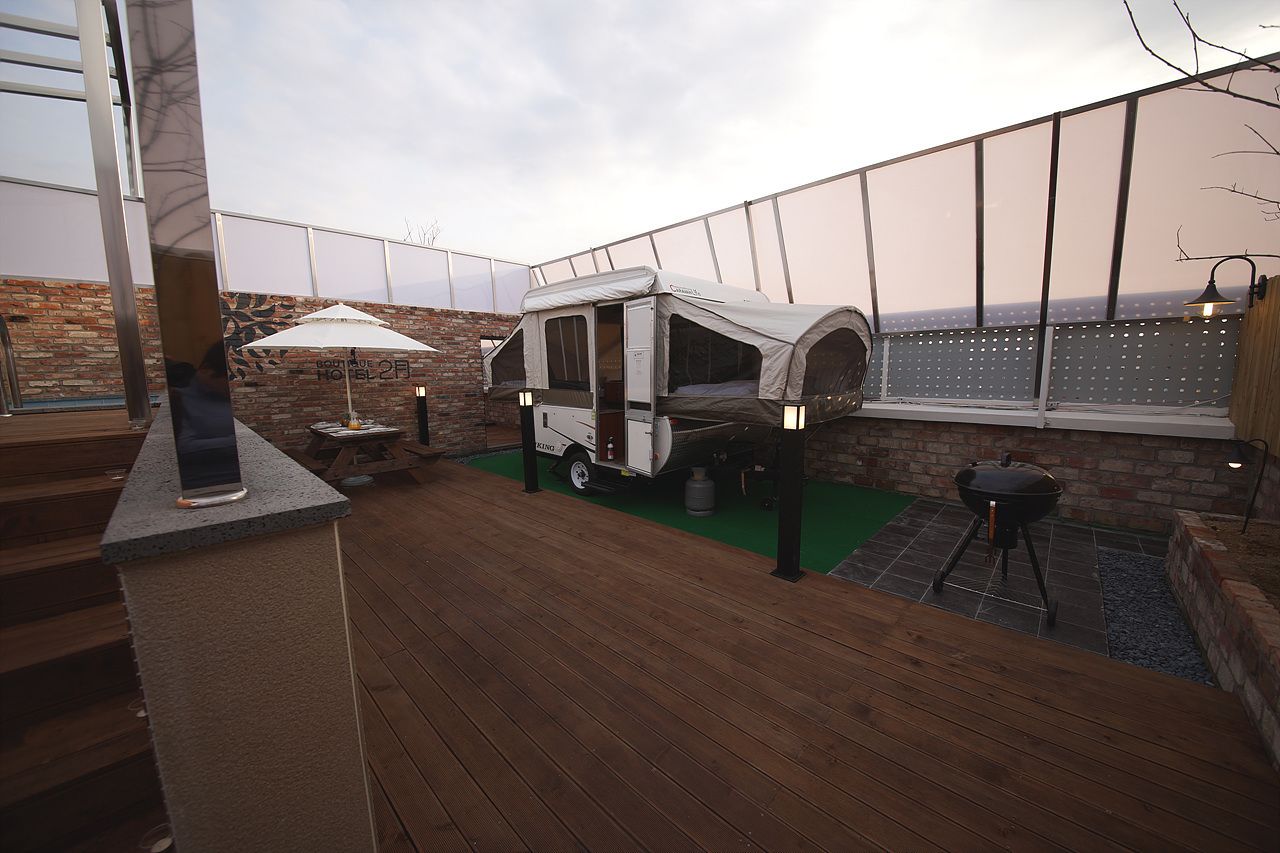 A rooftop patio with a portable camping setup, including a tent and a grill.