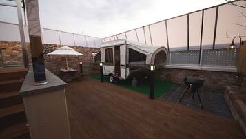 A rooftop patio with a portable camping setup, including a tent and a grill.