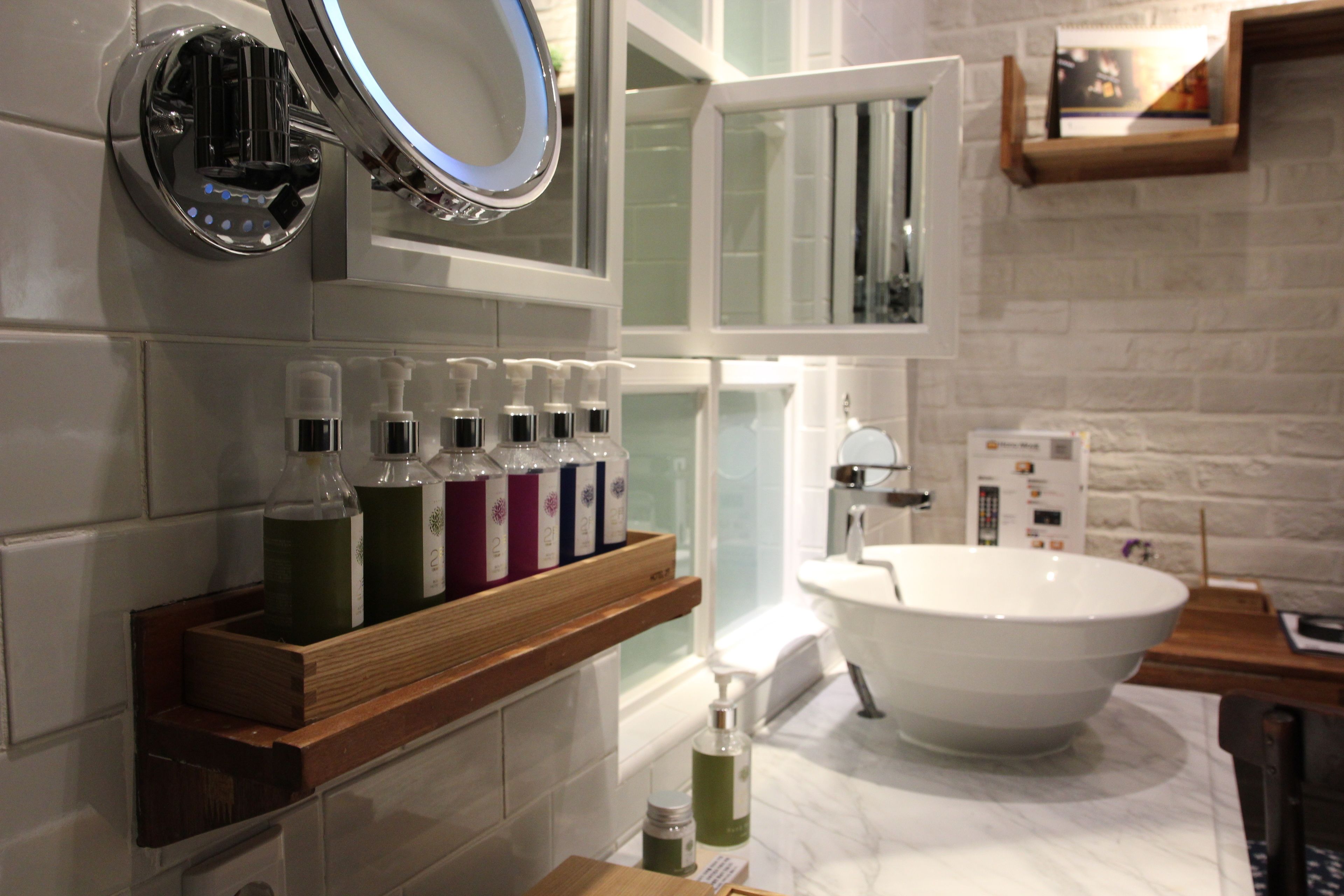 A bathroom with a freestanding bathtub, a wooden shelf with toiletries, and a mirror above the shelf.