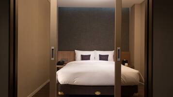 Una habitación de hotel con una cama grande, una mesita de noche y un teléfono instalado en la pared.