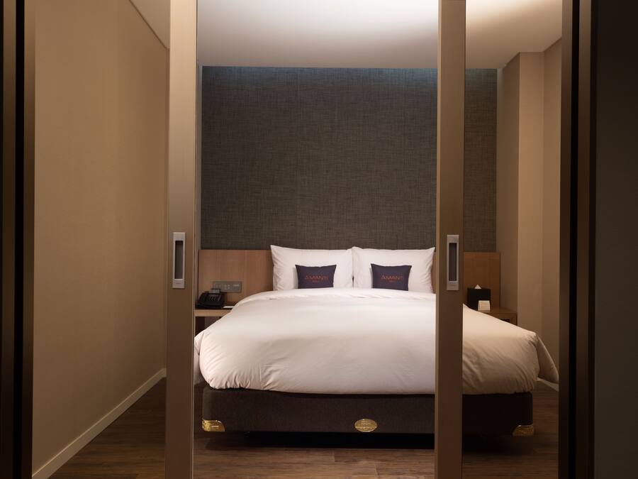 Una habitación de hotel con una cama grande, una mesita de noche y un teléfono instalado en la pared.