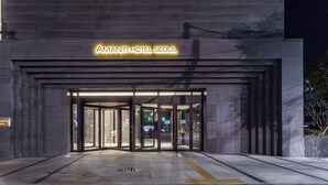 La entrada del Hotel Amanti Seoul, con puerta de cristal y un letrero en la parte superior.
