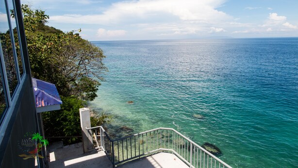 Un balcón con vista despejada al océano, una barandilla y un letrero que indica el Resort Jaynet Oceanview.
