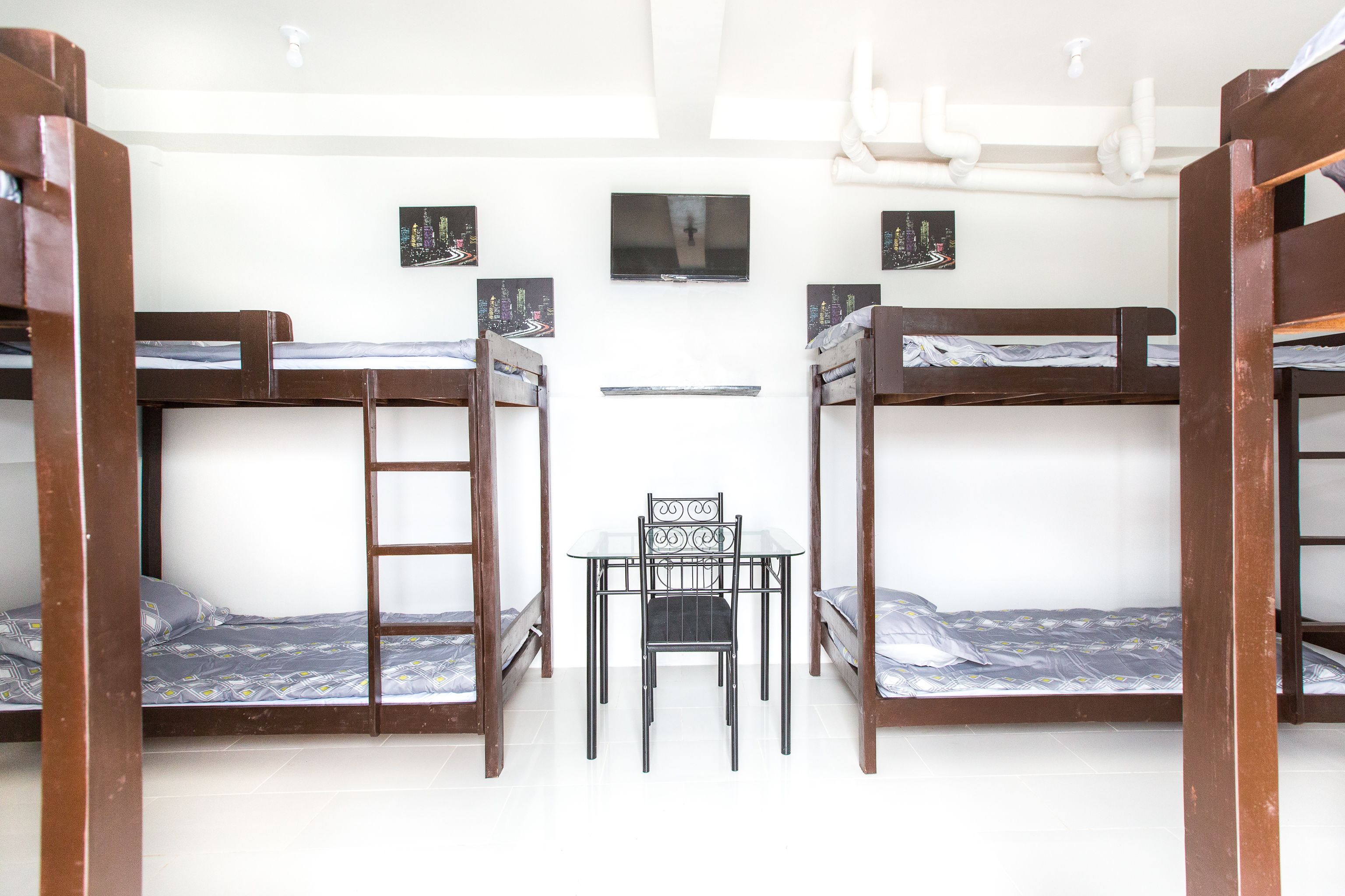 A dormitory room with bunk beds, a small table, and chairs.