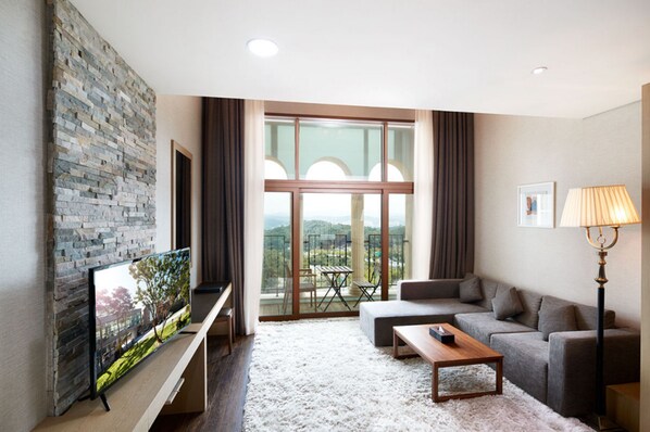 Una sala de estar moderna con una pared de piedra, un televisor de pantalla plana, un sofá, una mesa de centro y una lámpara de pie.