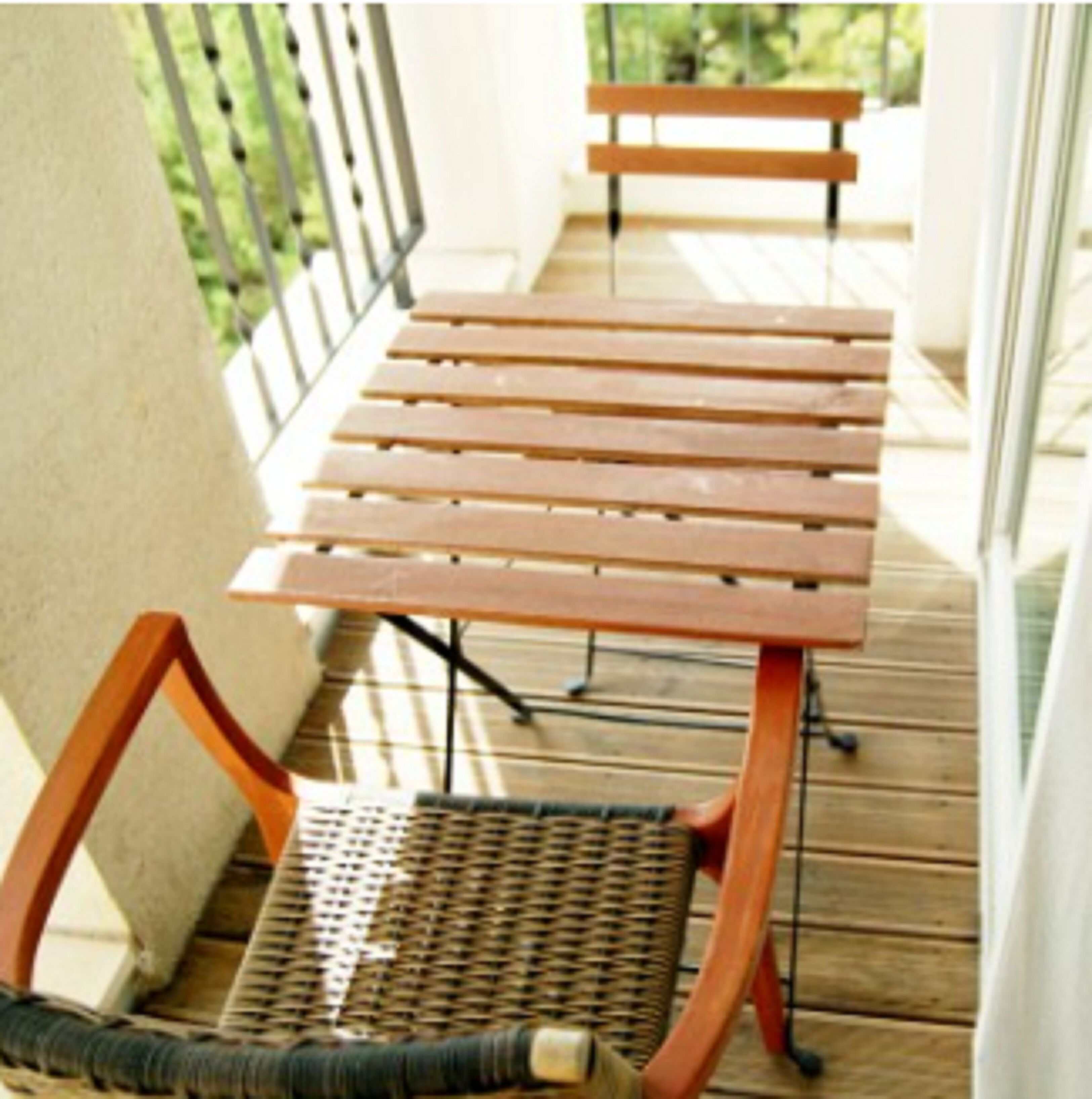A wooden deck with a wicker chair and a wooden bench.