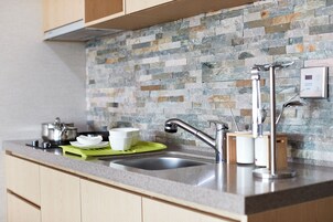 Una cocina con encimera de granito, pileta de acero inoxidable y salpicadero de piedra.