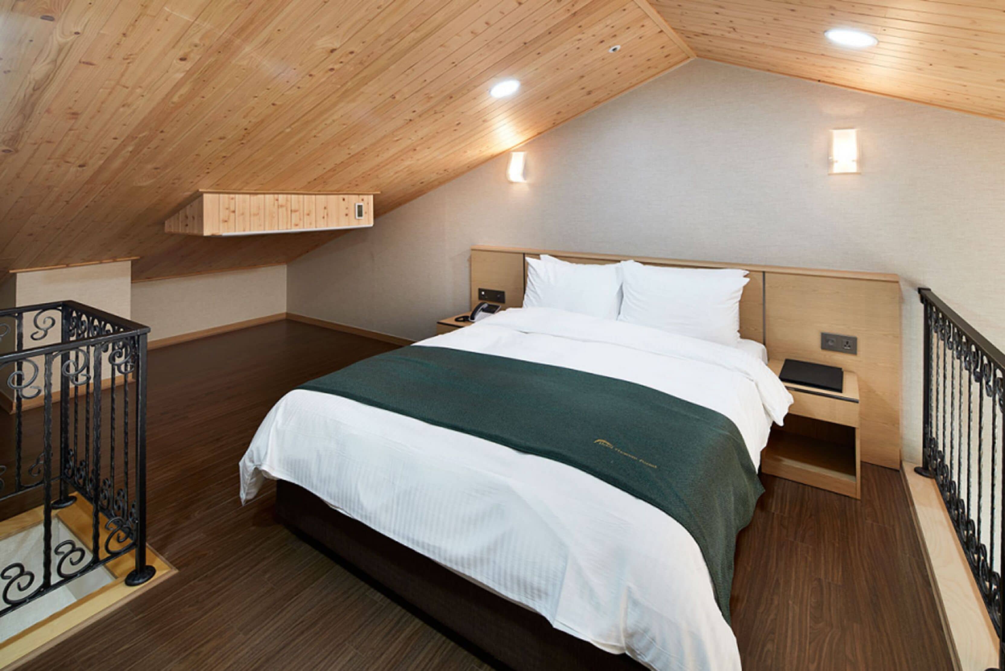 Una camera da letto con soffitto in legno, un letto grande, comodini e un tavolino da notte.