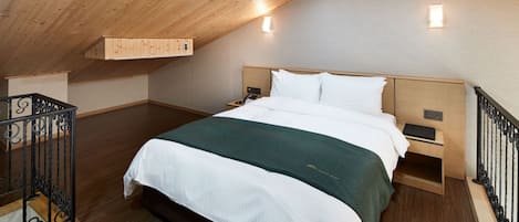 Una camera da letto con soffitto in legno, un letto grande, comodini e un tavolino da notte.