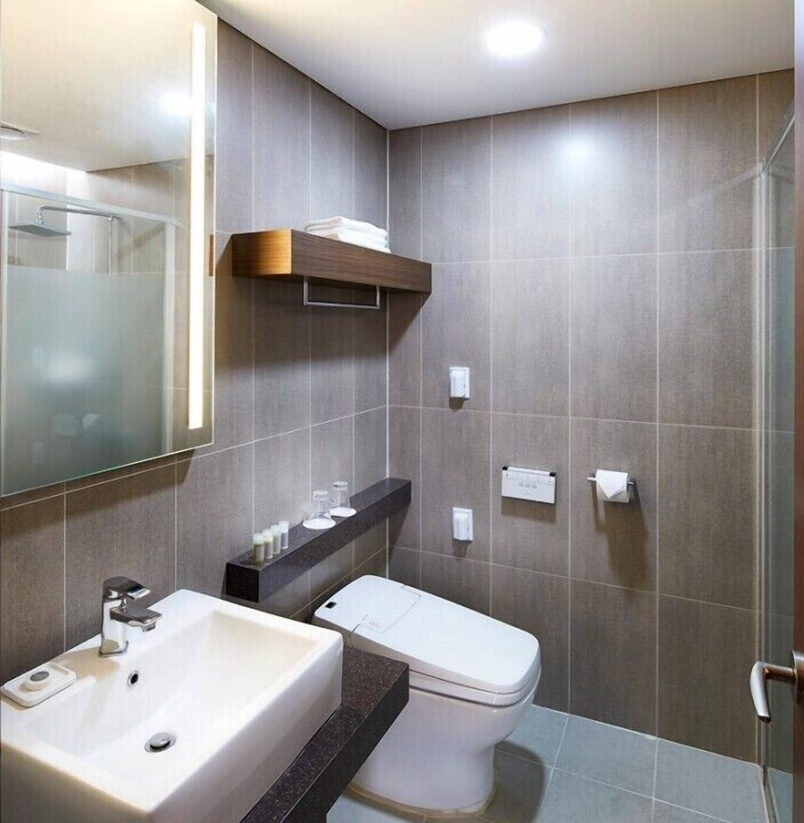 Un bagno moderno con uno specchio grande, un lavandino, un water e un box doccia.