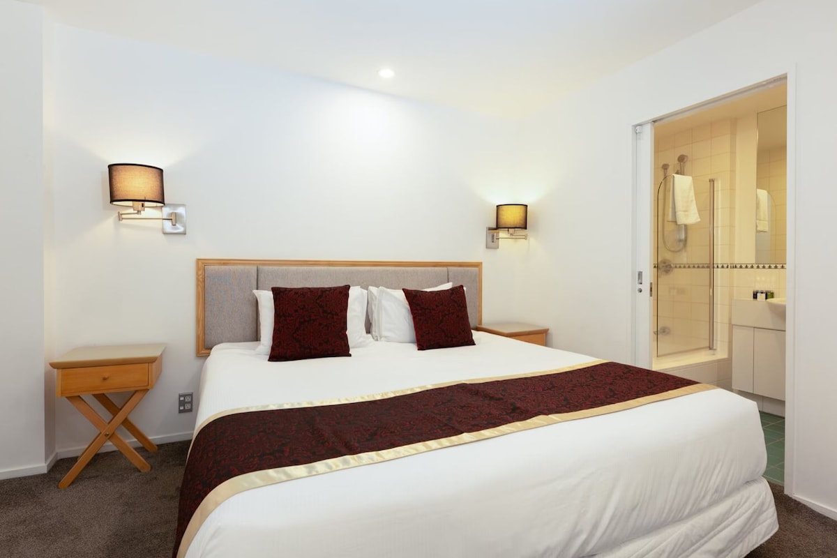 A hotel room with a bed, bedside tables, and a wardrobe.
