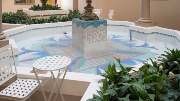 Un atrium à plusieurs niveaux, doté d’une fontaine centrale, d’espaces de détente et d’une piscine ornée de motifs en mosaïque.