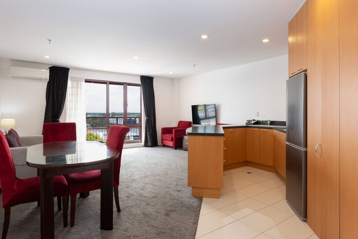 A modern apartment with a dining area, kitchen, and balcony.