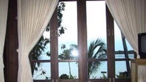 Ein Zimmer mit großen Fenstern, Vorhängen und einem Fernseher.